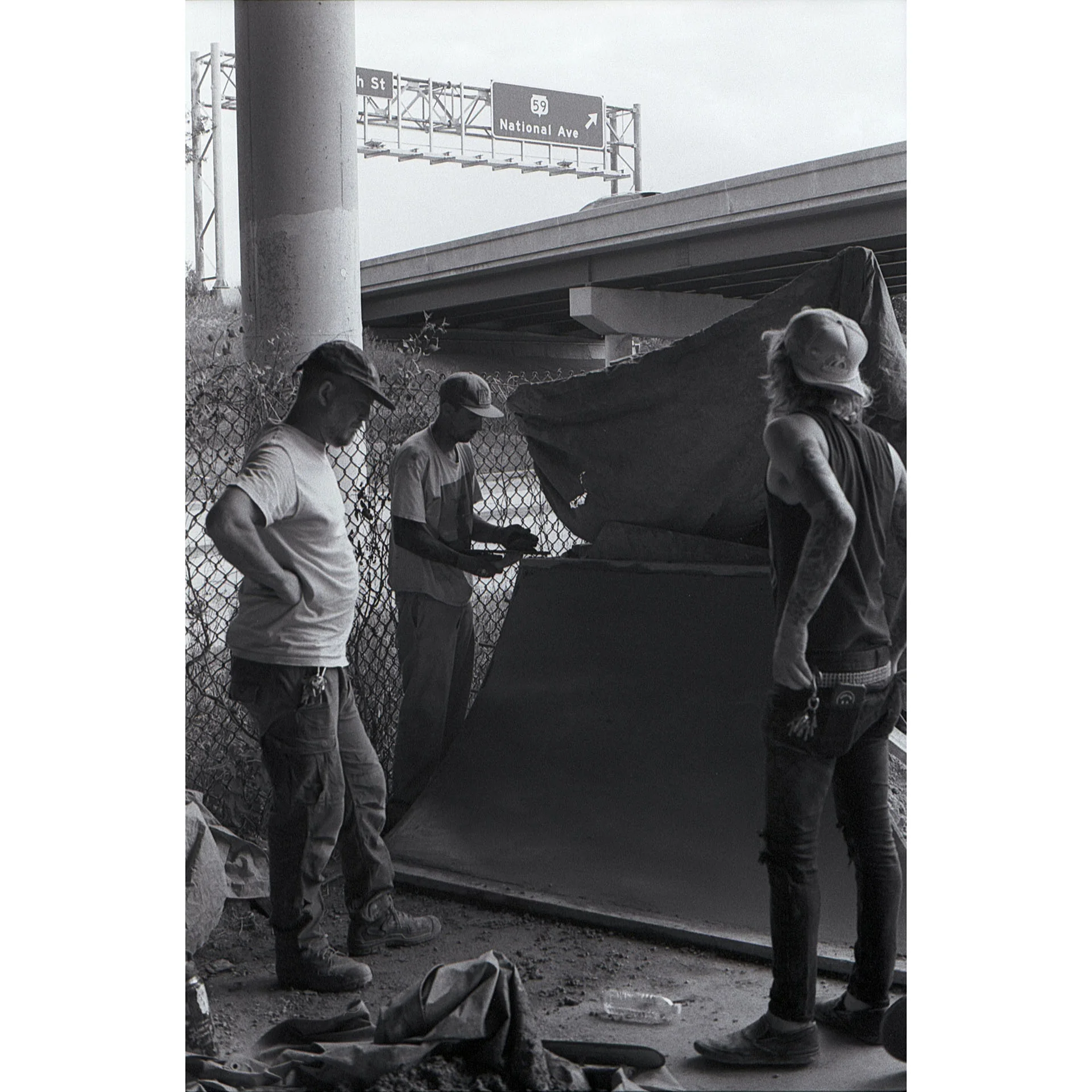Black and white photo of Aaron Polansky, Coach Boach, and Robby in deep contemplation on how to finish pouring a concrete transition.